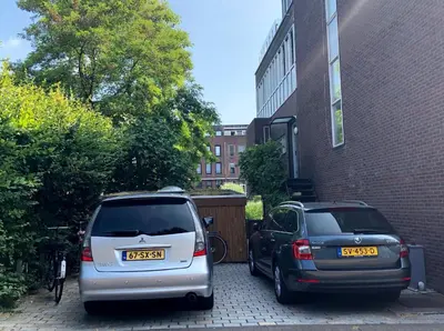 two cars parked in a parking lot next to a building at The Green Tunnel in Amsterdam