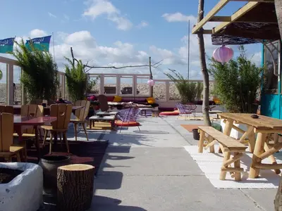 a patio with wooden tables and chairs and benches at The Green Tunnel in Amsterdam