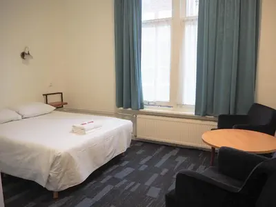 a room with a bed and two chairs and a table at Euphemia Budget Old City Canal Zone in Amsterdam