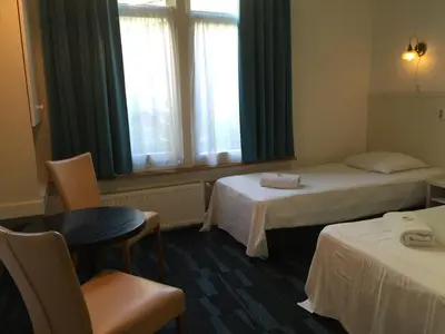 a hotel room with two beds and a table and chairs at Euphemia Budget Old City Canal Zone in Amsterdam