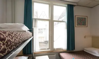 a bedroom with a bunk bed and a large window at Euphemia Budget Old City Canal Zone in Amsterdam