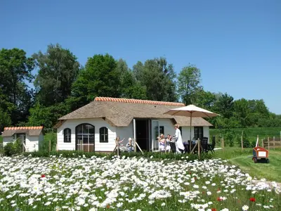 a group of people in front of a house with flowers at Mariahoeve-Logies #Veenhuisje in Woubrugge