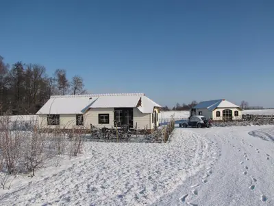 a house with footprints in the snow next to a road at Mariahoeve-Logies #Veenhuisje in Woubrugge