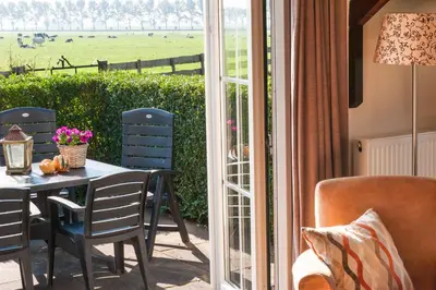 a patio with a table and chairs next to a sliding glass door at Mariahoeve-Logies #Veenhuisje in Woubrugge