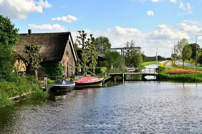 two boats are docked in a river next to a house at Mariahoeve-Logies #Veenhuisje in Woubrugge
