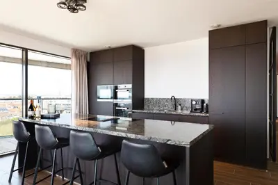 a kitchen with a large island with bar stools at Maris Apartments in Egmond aan Zee