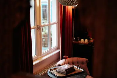 a table with a glass of wine next to a window at Rosalia's Menagerie Cocktail bar & InnUpstairs in Amsterdam