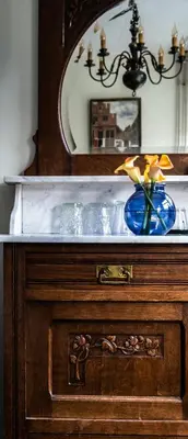 a wooden cabinet with a blue vase with a flower in it at Rosalia's Menagerie Cocktail bar & InnUpstairs in Amsterdam
