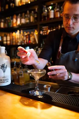 a man standing at a bar preparing a drink at Rosalia's Menagerie Cocktail bar & InnUpstairs in Amsterdam