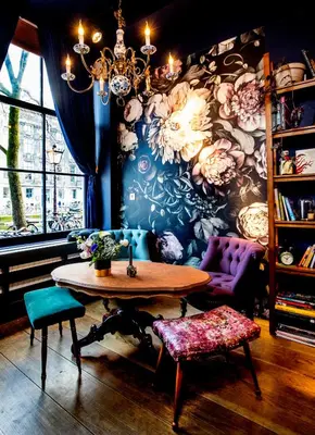 a table and chairs in a room with a floral wall at Rosalia's Menagerie Cocktail bar & InnUpstairs in Amsterdam