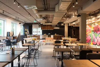 a dining room with tables and chairs and a cafeteria at Via Suites in Amsterdam