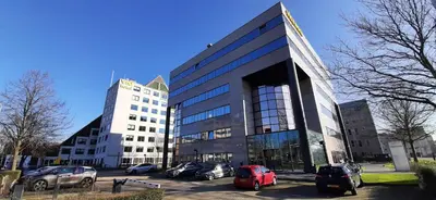 a large building with cars parked in a parking lot at Via Suites in Amsterdam
