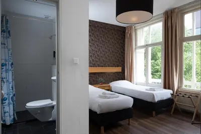 a hotel room with two beds and a bathroom at Hotel Amsterdam Inn in Amsterdam