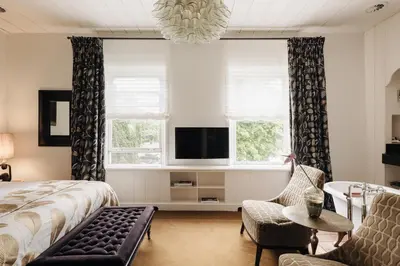a bedroom with a bed and a tv and windows at Inn on the Lake in Broek in Waterland