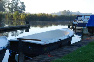 a boat is docked at a dock on a lake at Dobberhuisje in Nieuwkoop