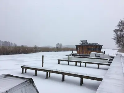a snow covered field with benches and a building at Dobberhuisje in Nieuwkoop