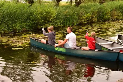 a group of people sitting in a canoe on a river at Dobberhuisje in Nieuwkoop