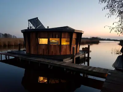 a tiny house on a dock on a body of water at Dobberhuisje in Nieuwkoop