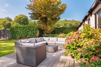 a patio with wicker furniture and flowers in a yard at Villa De Stolp in Schoorl