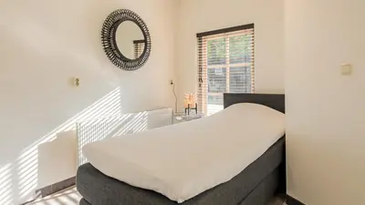 a bedroom with a bed and a mirror on the wall at Villa De Stolp in Schoorl