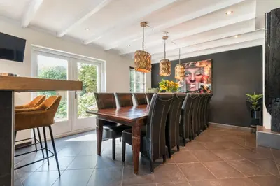 a dining room with a wooden table and chairs at Villa De Stolp in Schoorl