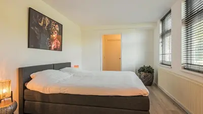 a bedroom with a bed and a painting on the wall at Villa De Stolp in Schoorl