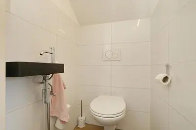 a white bathroom with a toilet and a sink at Paleisje Noordwijk in Noordwijk