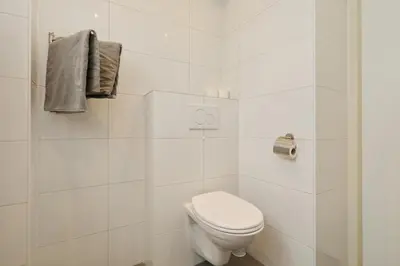 a white bathroom with a toilet and towels at Paleisje Noordwijk in Noordwijk