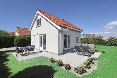 a small white house with chairs and a patio at Paleisje Noordwijk in Noordwijk