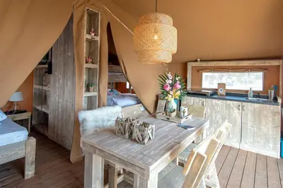 a dining room with a wooden table in a tent at Marinaparcs Almere in Almere