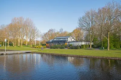 a building next to a river with a house at Studio Haarlemenmeer in Cruquius