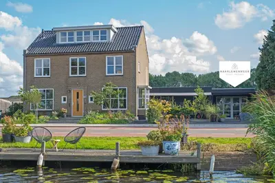 a house on the water with two chairs on a dock at Studio Haarlemenmeer in Cruquius