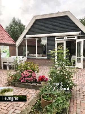 a house with a garden with flowers in front of it at Holiday-Home HELMGRAS 5p. Amsterdam and the beach in Opmeer