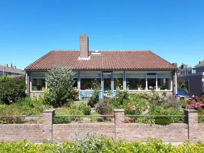 a house with a brick fence in front of it at B&B De Blauwe Tulp in Noord-Scharwoude