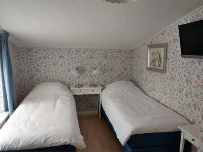 a bedroom with two beds and a tv on the wall at B&B De Blauwe Tulp in Noord-Scharwoude