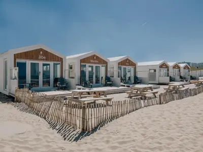 a row of lodges on the beach with picnic tables at BUDDHA BEACH BUNGALOWS Adults Only in Zandvoort