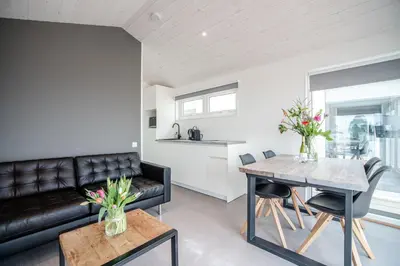 a living room with a black leather couch and a table at BUDDHA BEACH BUNGALOWS Adults Only in Zandvoort