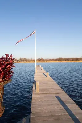 a dock on the water with a flag on it at Restaurant-Hotel de Watergeus in Noorden