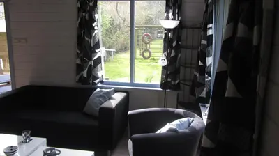 a living room with a couch and a chair and a window at Vakantiehuis Duin Bos en Zee in Schoorl