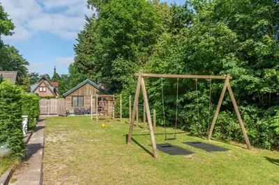 a playground with a swing set in a yard at Vakantiehuis Duin Bos en Zee in Schoorl