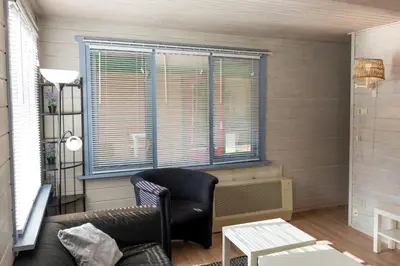 a living room with a chair and a window at Vakantiehuis Duin Bos en Zee in Schoorl