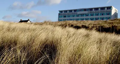 a building on top of a hill with tall grass at Hotel de Baak Seaside in Noordwijk aan Zee