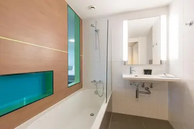 a bathroom with a tub and a sink and a mirror at Hotel de Baak Seaside in Noordwijk aan Zee