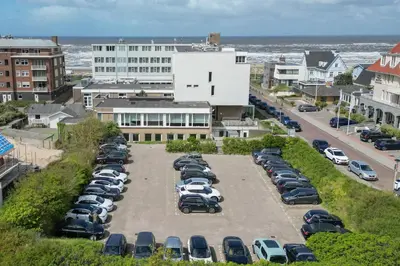 a parking lot with cars parked in front of a building at Hotel de Baak Seaside in Noordwijk aan Zee
