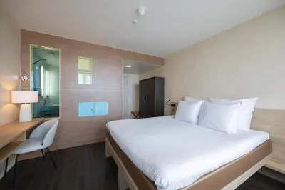 a hotel room with a large bed and a desk at Hotel de Baak Seaside in Noordwijk aan Zee