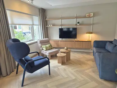 a living room with a tv and a couch and a chair at Hotel de Baak Seaside in Noordwijk aan Zee
