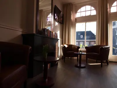 a living room with chairs and tables and a window at Hotel Clemens in Amsterdam