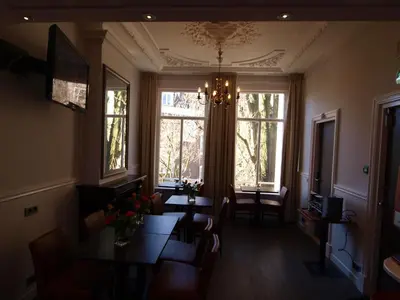 a dining room with a table and two windows at Hotel Clemens in Amsterdam
