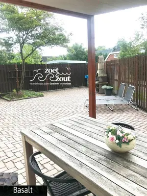 a wooden table with a vase of flowers on a patio at Holiday Home BASALT 6 p Amsterdam and the beach in Opmeer