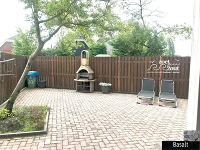 a backyard with two chairs and a grill and a fence at Holiday Home BASALT 6 p Amsterdam and the beach in Opmeer